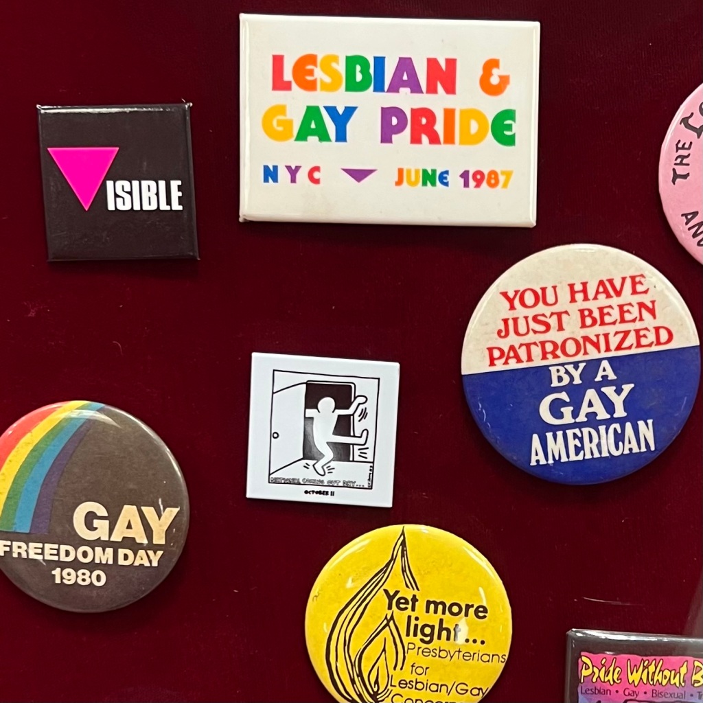 A collection of colorful pins and buttons which support LGBTQ+ rights on display.